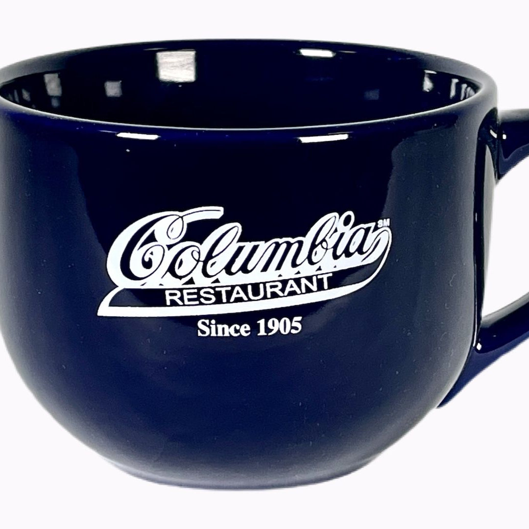 A 24 ounce navy blue ceramic mug with the Columbia logo printed in white.