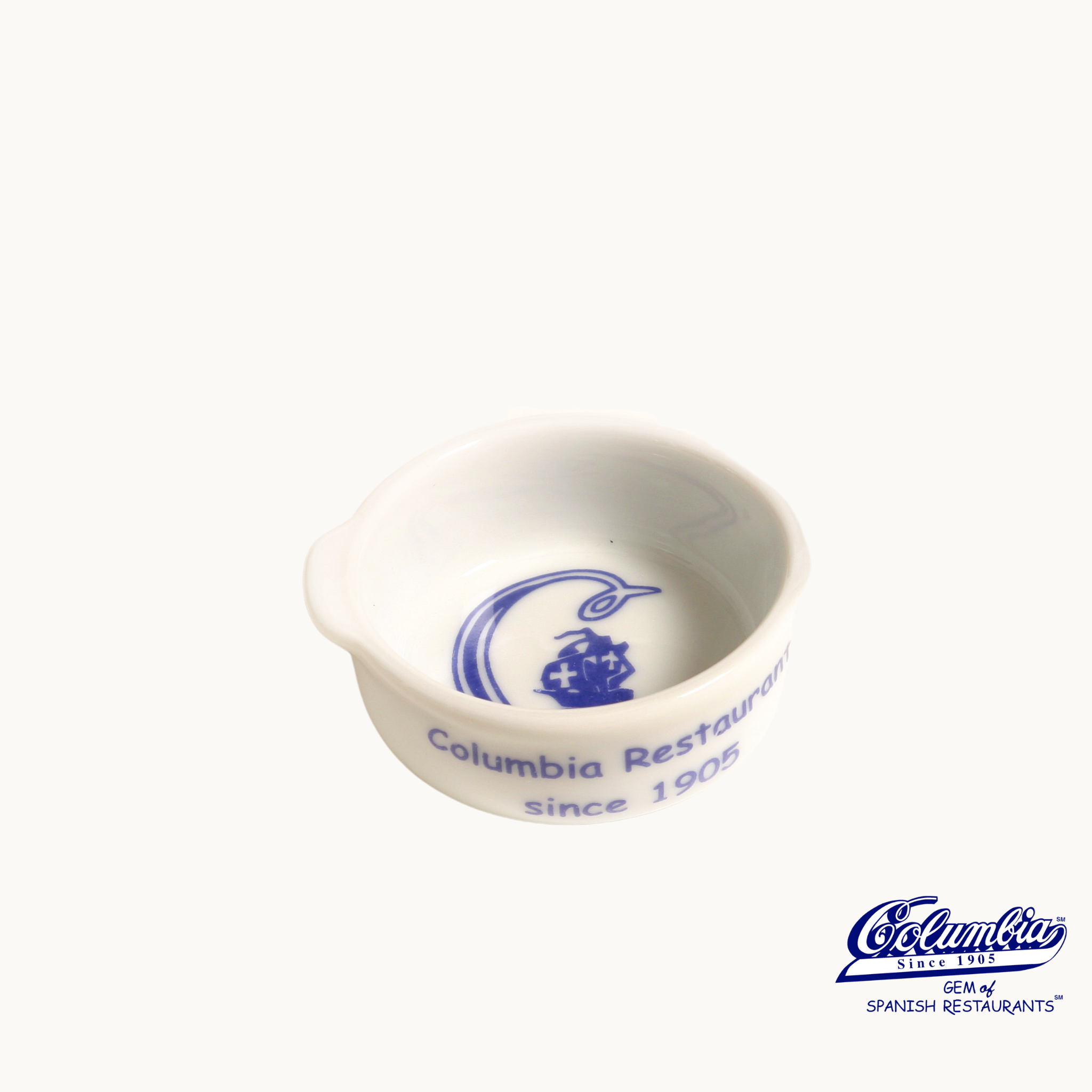 Small white ceramic bowl with blue Columbia Restaurant logo on a white background