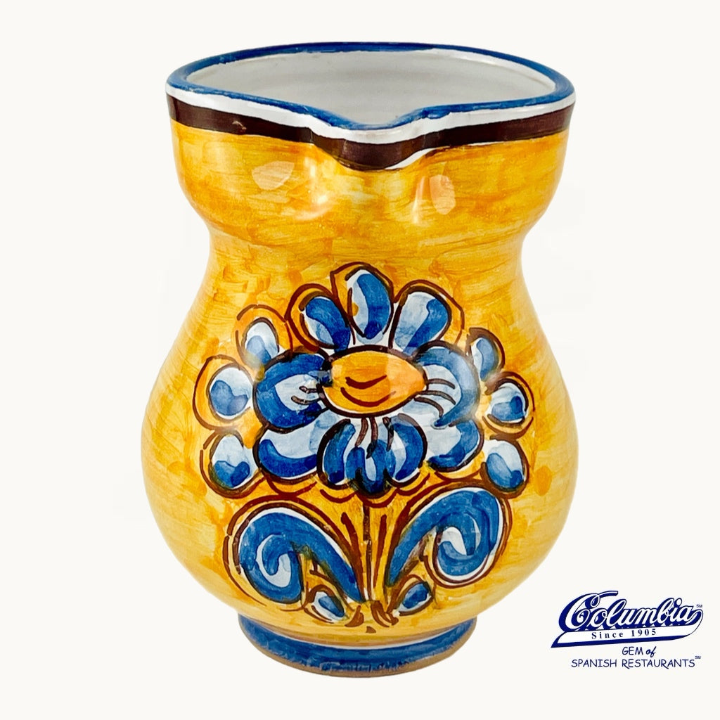 Ceramic vase with blue floral design on a yellow background, featuring the Columbus brand logo.