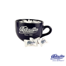 Black mug with Columbia Restaurant branding, filled with marshmallows and candy on a white background.