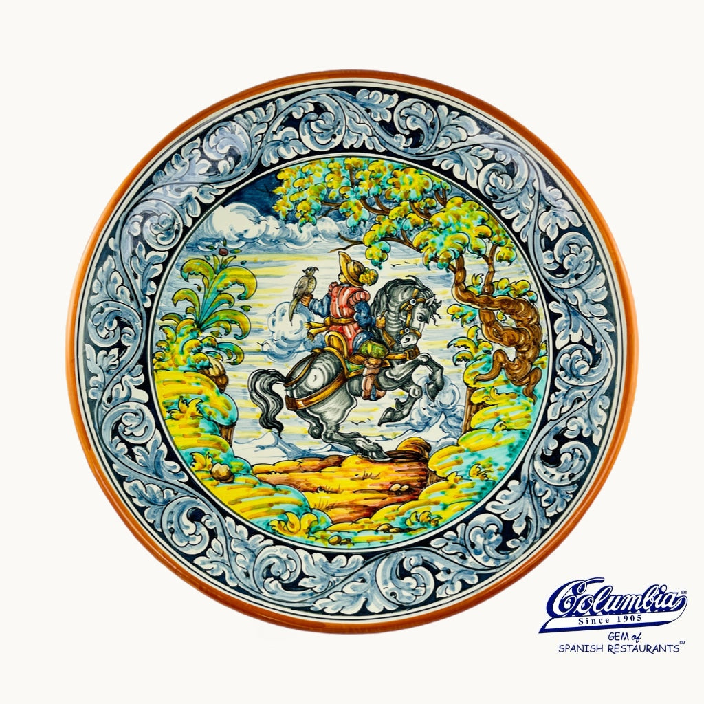 A decorative plate that has a man riding a horse holding a bird