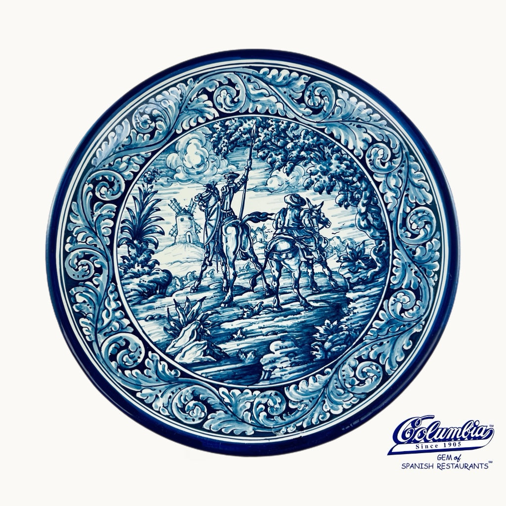 Decorative plate with blue and white intricate design, featuring a scene of people on horseback.