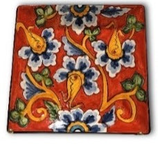 A square ceramic plate with a red background and a multicolor floral pattern.