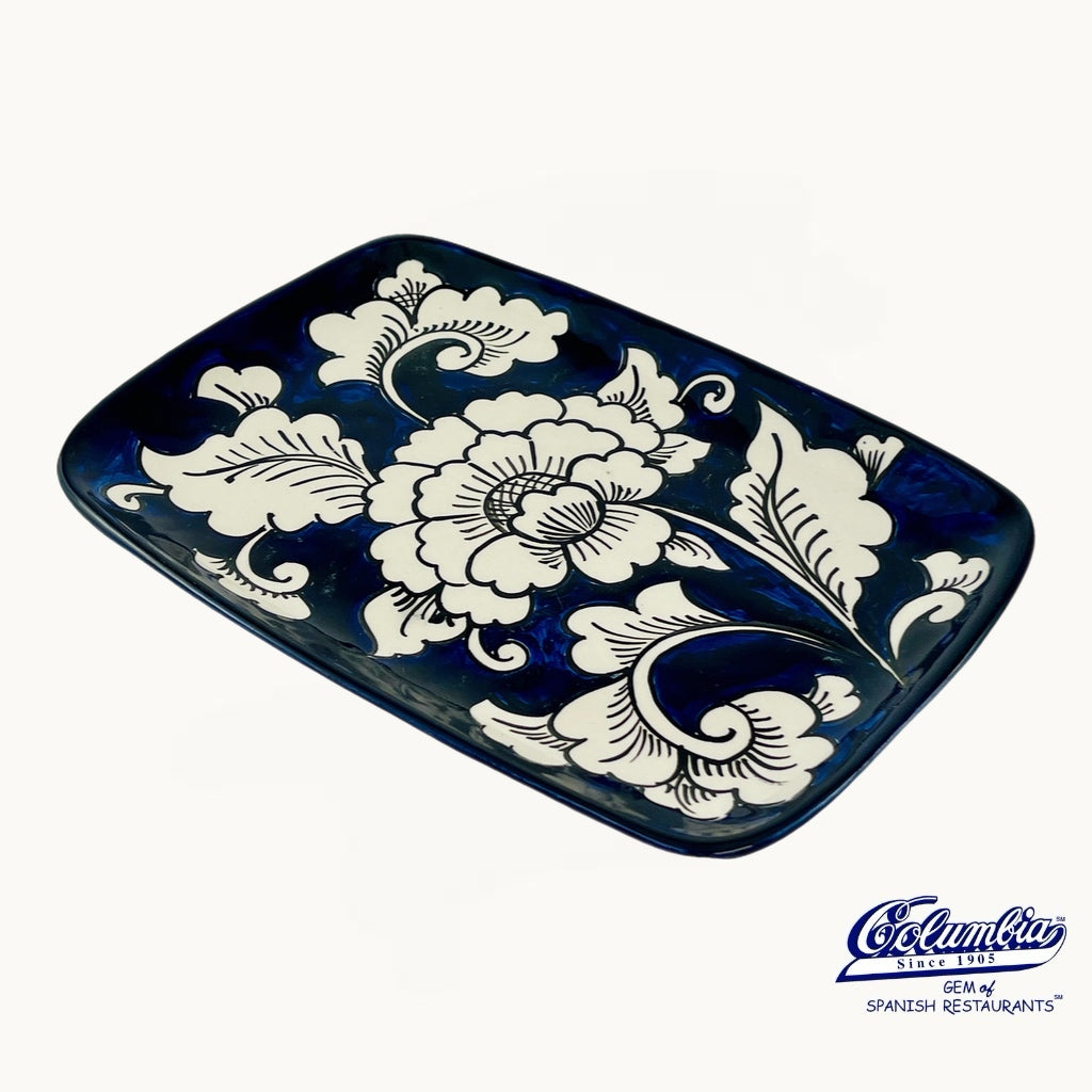 Decorative ceramic tray with white floral patterns on a blue background, featuring the Caramelo logo.