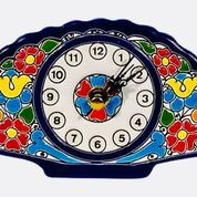 A fan-shaped wall clock with a colorful floral pattern on the clock face, set against a white background.