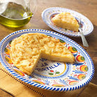 Spanish tortilla served on a hand-painted ceramic plate with colorful floral border design, accompanied by a smaller matching plate holding a slice.