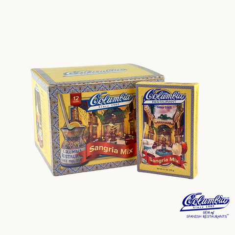 The image shows a 12 pack case of Columbia Sangria Mix, with individual sachets of the mix visible in front of the box. The packaging is predominantly in colors blue and yellow, with Spanish flag-like elements and traditional imagery.