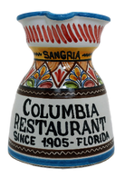 A ceramic pitcher with hand-painted patterns, predominantly white with a colorful geometric design, and text that reads 'COLUMBIA RESTAURANT SINCE 1905 - FLORIDA'.